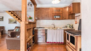 Une cuisine avec des meubles en bois, un fourneau et un coin repas comprenant un canapé et une table.