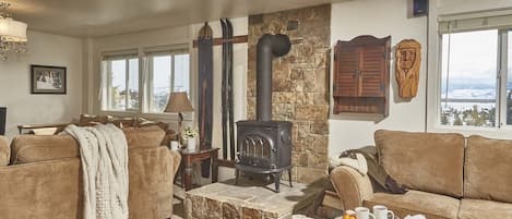 A cozy living room with a stone fireplace, two sofas, a coffee table, and a view of the outdoors.