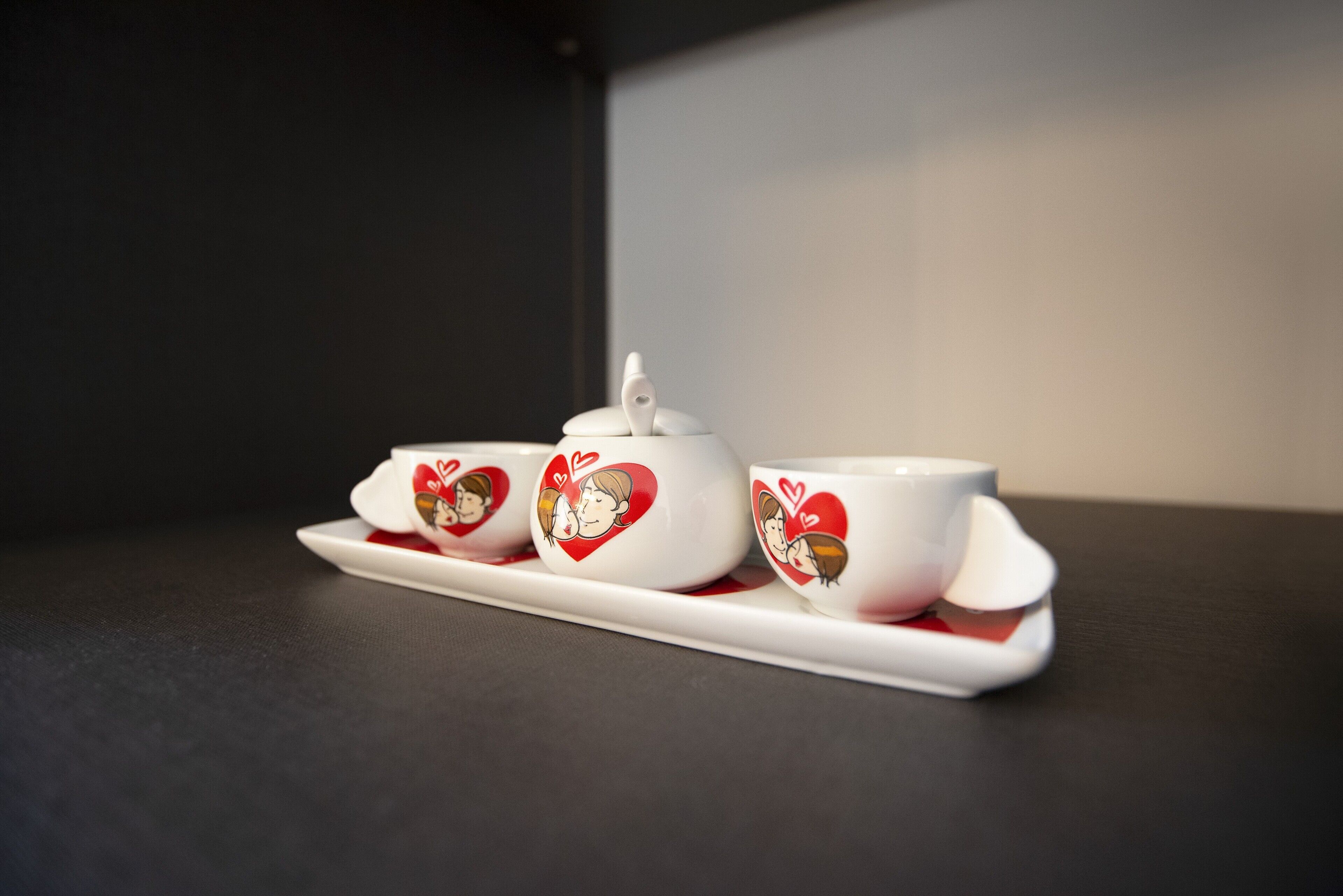 A white ceramic tea set with heart designs on a dark surface.