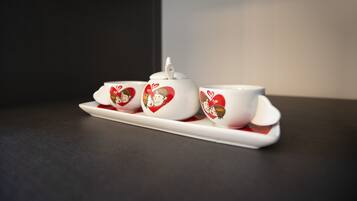 A white ceramic tea set with heart designs on a dark surface.