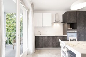A modern kitchen with a balcony, white cabinets, and a dining area.