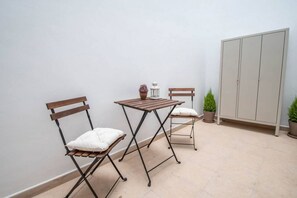 A small, enclosed patio area with two wooden chairs and a table, a white wall, and a grey cabinet. - Duplex Flamingo Cadiz (Cádiz)