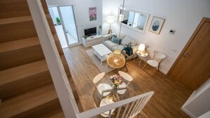 A modern living room with a sofa, coffee table, and a dining area with chairs and a table. - Duplex Flamingo Cadiz (Cádiz)