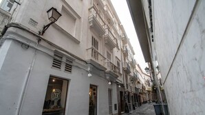 A narrow street with buildings on either side, featuring a restaurant with a visible logo and outdoor seating. - Duplex Flamingo Cadiz (Cádiz)