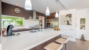 Una cucina moderna con isola centrale, sgabelli da bar, luci a sospensione e vista sull'esterno.