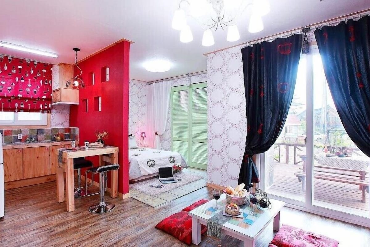 A compact room with a kitchenette, a dining area, and a bed.