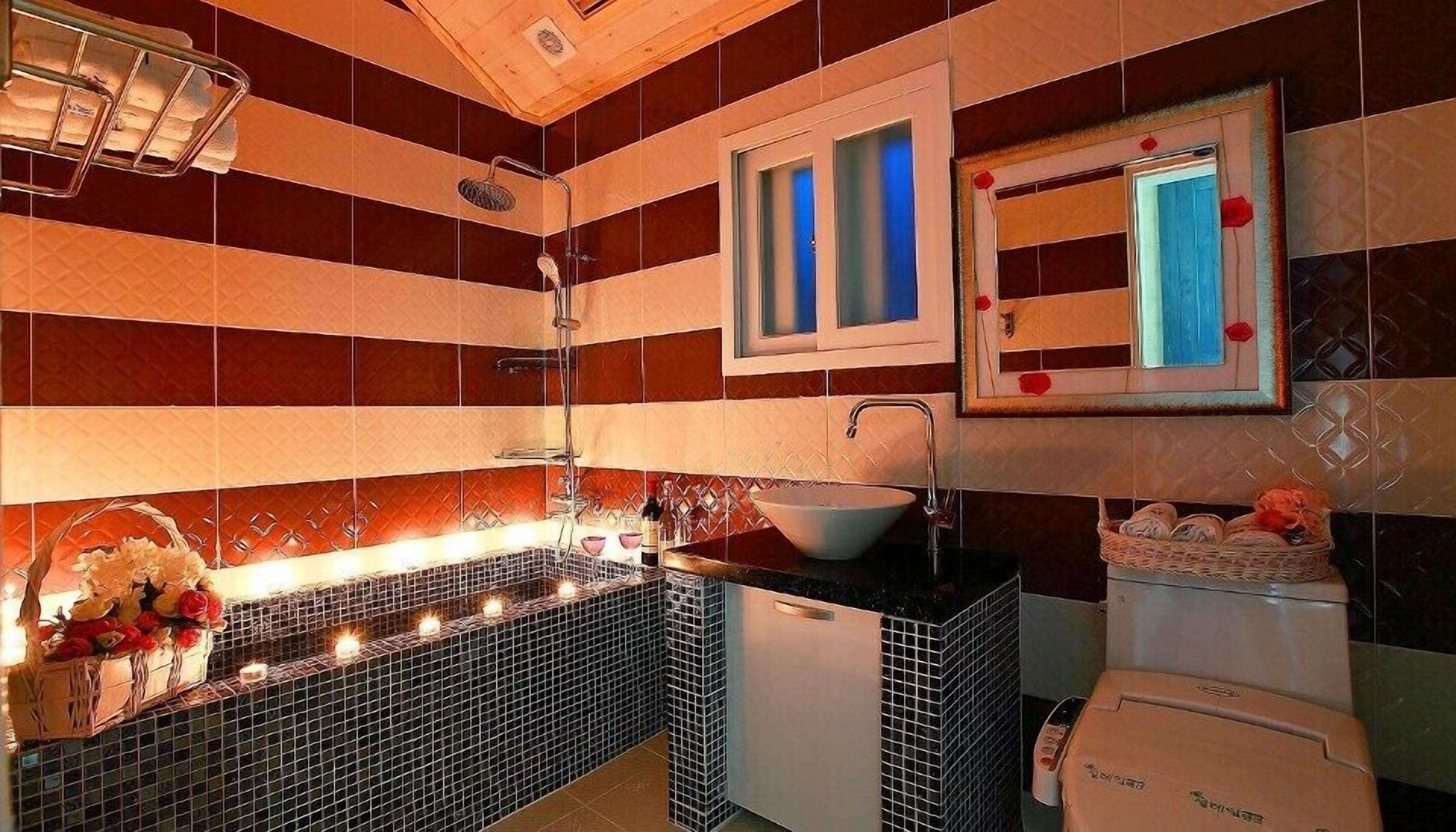 A bathroom with striped tile walls, a sink with a white basin, a mirror with a red frame, and a shower with a glass door.