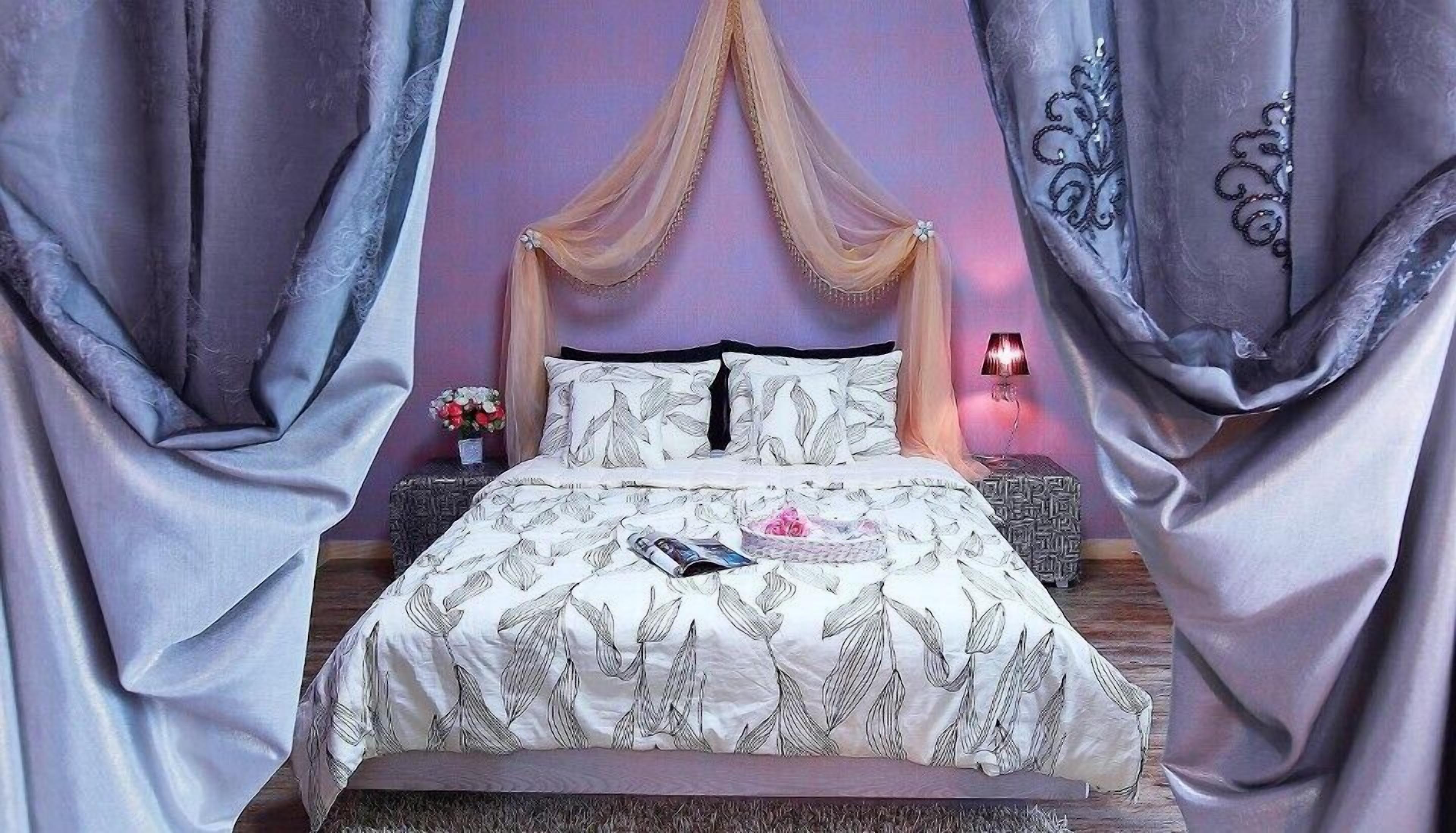 A bedroom with a canopy bed, a bedside table with a lamp, and a vase with flowers.