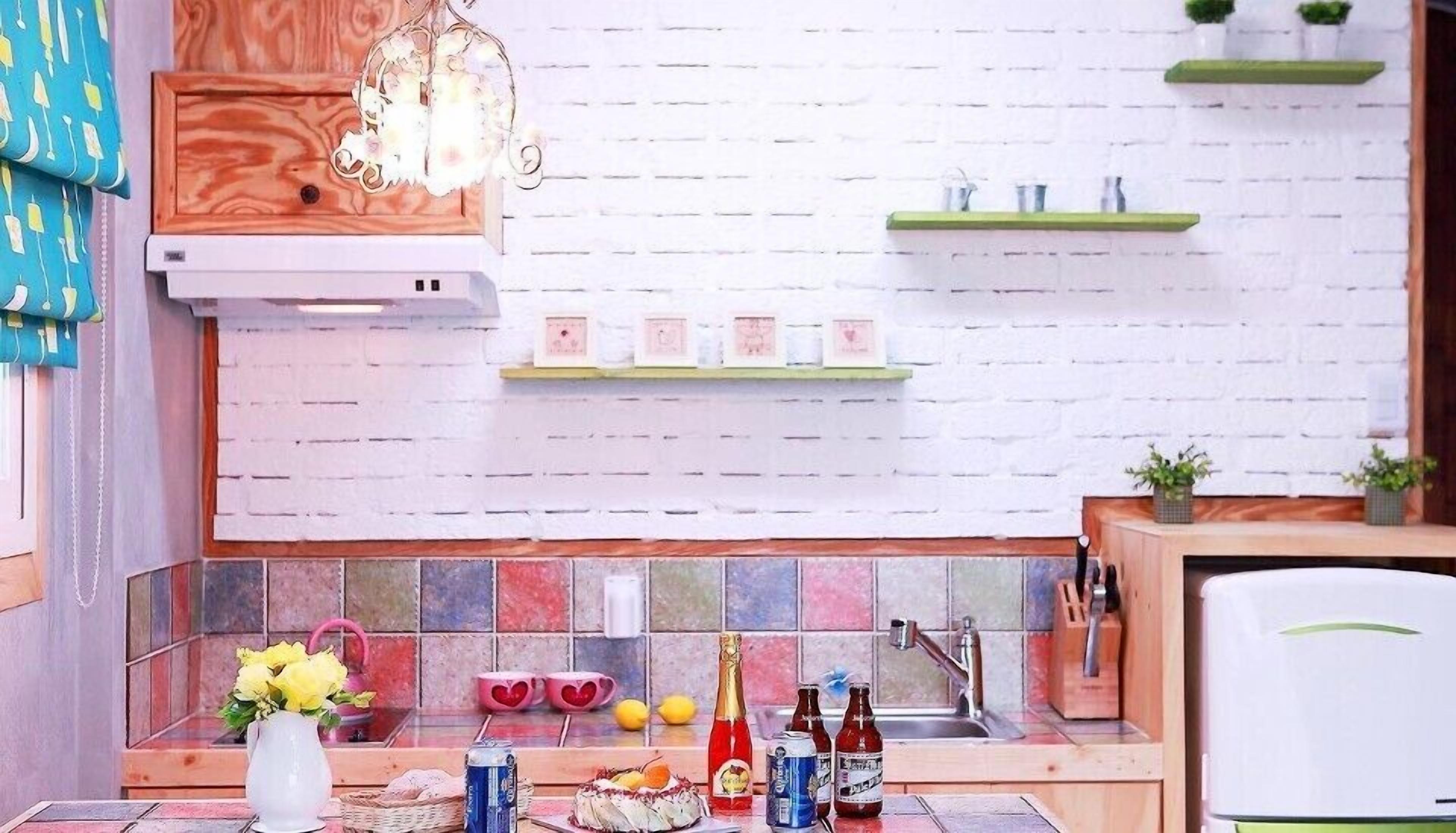 A kitchen with a white brick backsplash, wooden cabinets, and a tiled countertop. There are shelves with kitchen items, a sink, and a refrigerator.