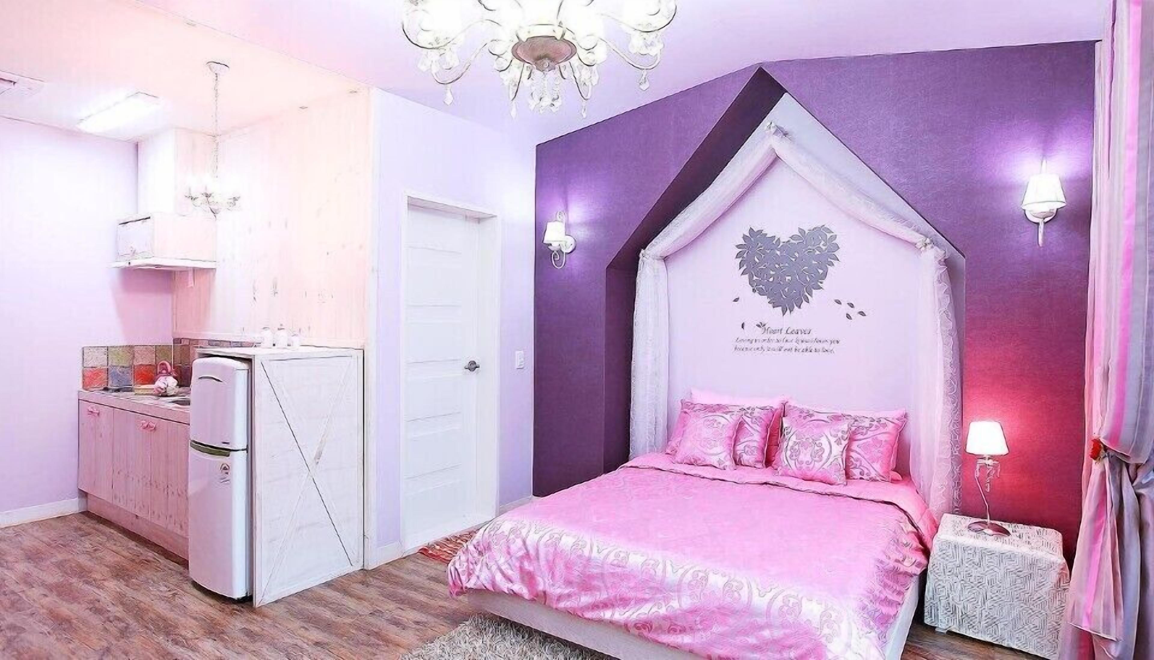 A bedroom with a bed, a dresser, a vanity, and a chandelier.