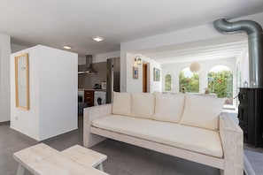 A modern living room with a sofa, a wooden coffee table, and a kitchen in the background.