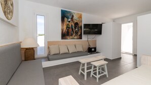 A modern hotel room with a sofa, a dining table, a TV, and a painting on the wall. - Holiday Home "Ca Sa Mola" with Terrace and Pool (Cala Blanca - Ciutadella de Menorca)