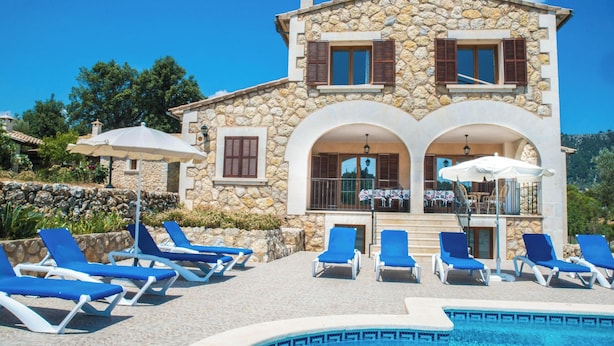 A stone villa with a pool, blue lounge chairs, and umbrellas. - Rural Villa with pool and a view – Villa Rote (Campanet)