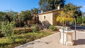 A stone building with a small window and a door, surrounded by greenery and a paved area. - Rural Villa with pool and a view – Villa Rote (Campanet)