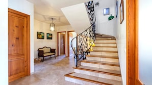 A staircase with a curved railing, a wooden door, a bench, and a wall with framed pictures. - Rural Villa with pool and a view – Villa Rote (Campanet)