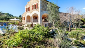 A stone villa with a pool, arched balconies, and lush greenery. - Rural Villa with pool and a view – Villa Rote (Campanet)