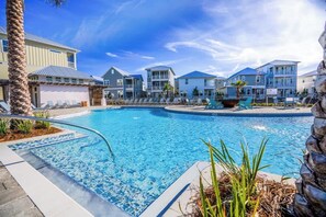 Une piscine avec des chaises longues et, en arrière-plan, une vue sur des immeubles à plusieurs étages.
