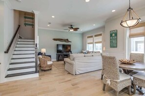 Un salon comprenant un canapé, des fauteuils, une table à manger et un escalier.