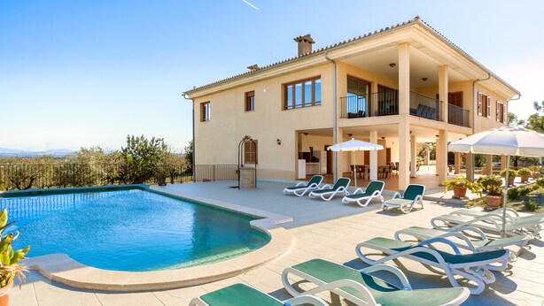 A two-story house with a swimming pool, lounge chairs, and a view of the landscape. - Rural Villa with pool and spectacular views – Villa Sastre (Campanet)