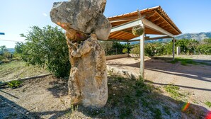 A rock formation with a pergola structure in the background. - Rural Villa with pool and spectacular views – Villa Sastre (Campanet)