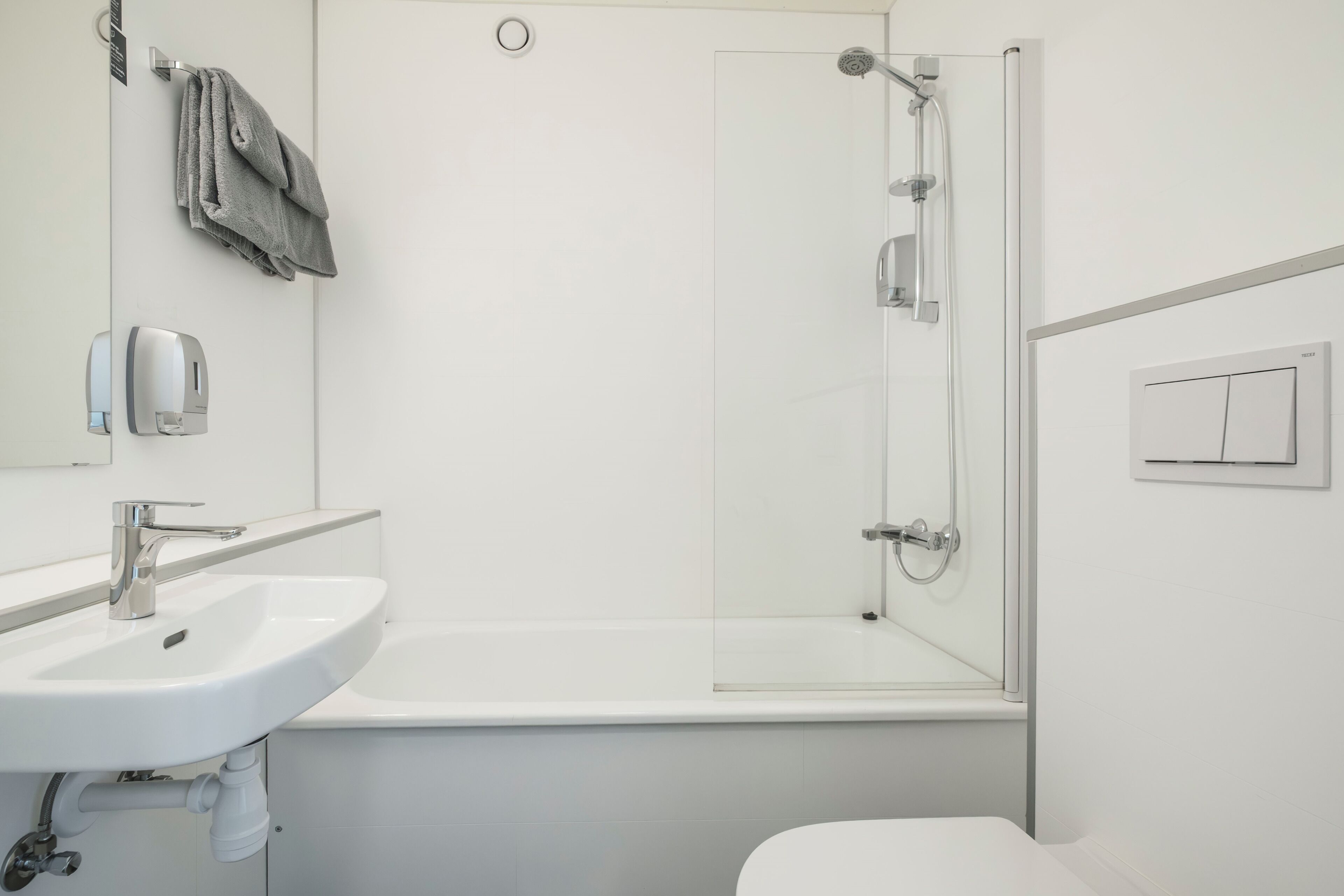 Een moderne badkamer met een wit wastafel, toilet en een douche met glazen wanden.