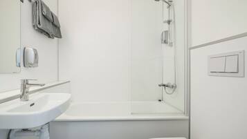 Een moderne badkamer met een wit wastafel, toilet en een douche met glazen wanden.