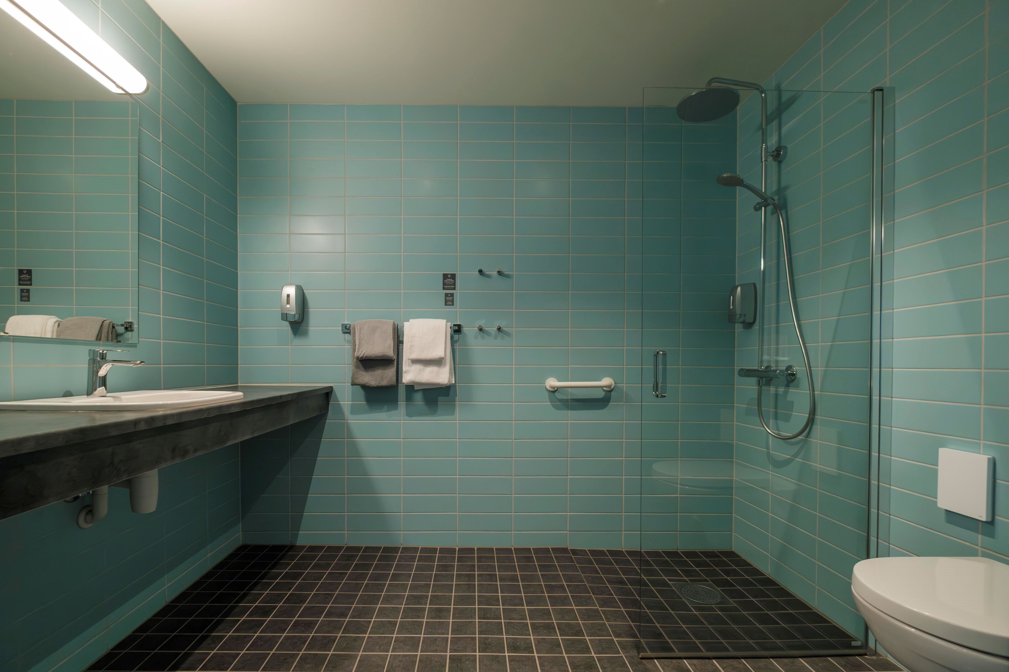 A bathroom with a sink, mirror, towel rack, toilet, and shower.