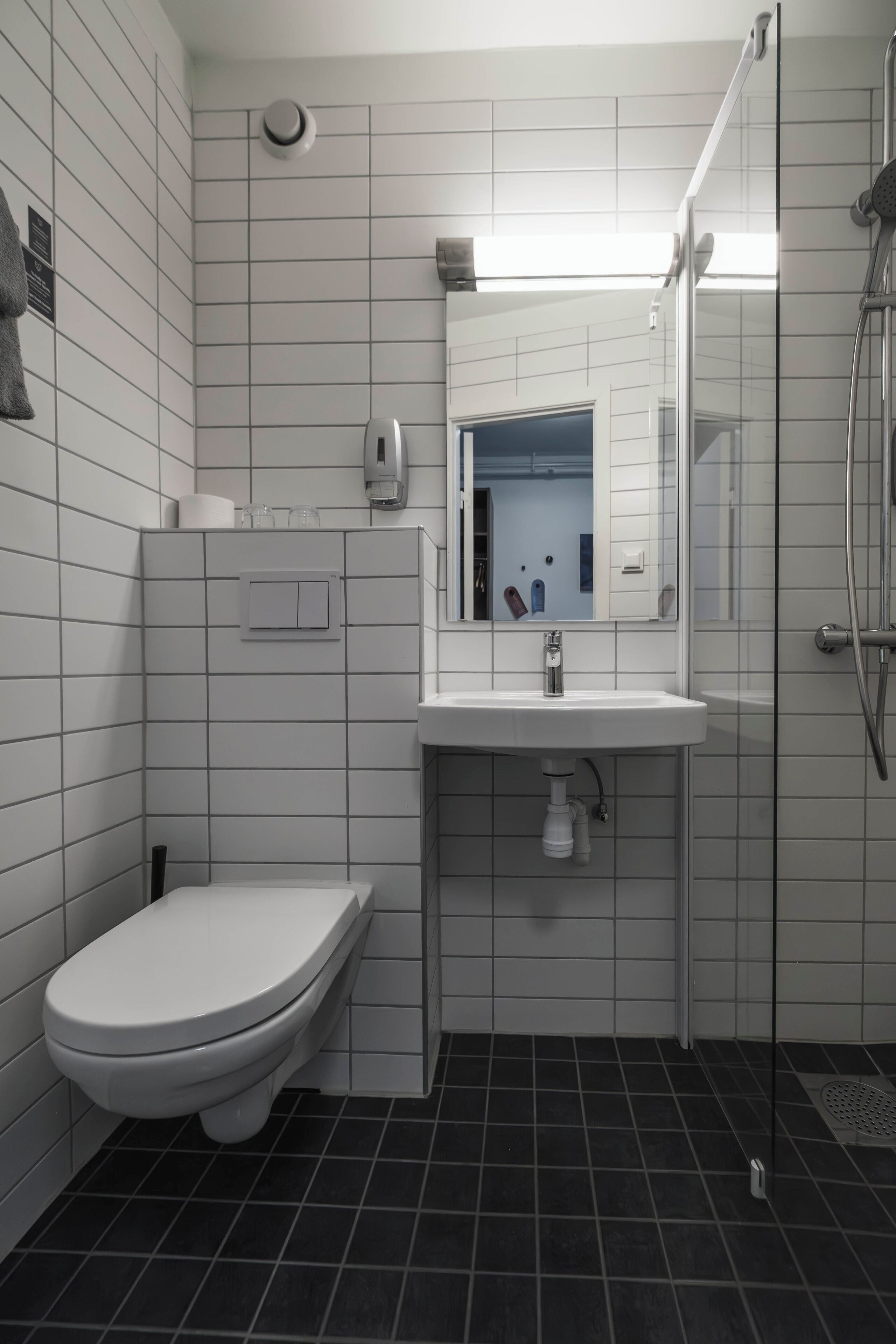 Un baño con inodoro blanco, lavamanos y ducha.