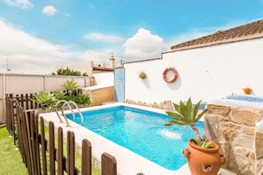 A rectangular swimming pool with a wooden fence, a stone wall, and a potted plant. - Family Home "La Lobita 2" Short Walk to Beach with Pool and Terrace (Conil de la Frontera)