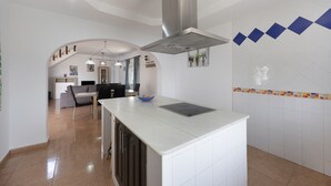Uma cozinha moderna com uma ilha central, uma área de jantar com sofá e cadeiras, e uma ilha de cozinha com uma tigela.