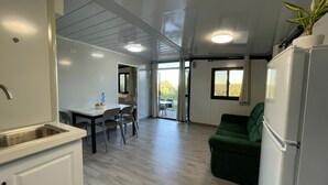 Eine moderne Küche mit Spüle, Esstisch, Stühlen und einem grünen Sofa.