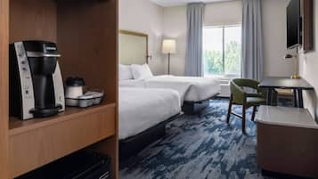Habitación de hotel con dos camas, un escritorio, una silla, cafetera y televisión.
