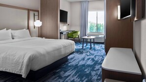 A hotel room with a large bed, a desk, a chair, a TV, and a window with a view. - Fairfield Inn & Suites by Marriott Rocky Mount (Rocky Mount)