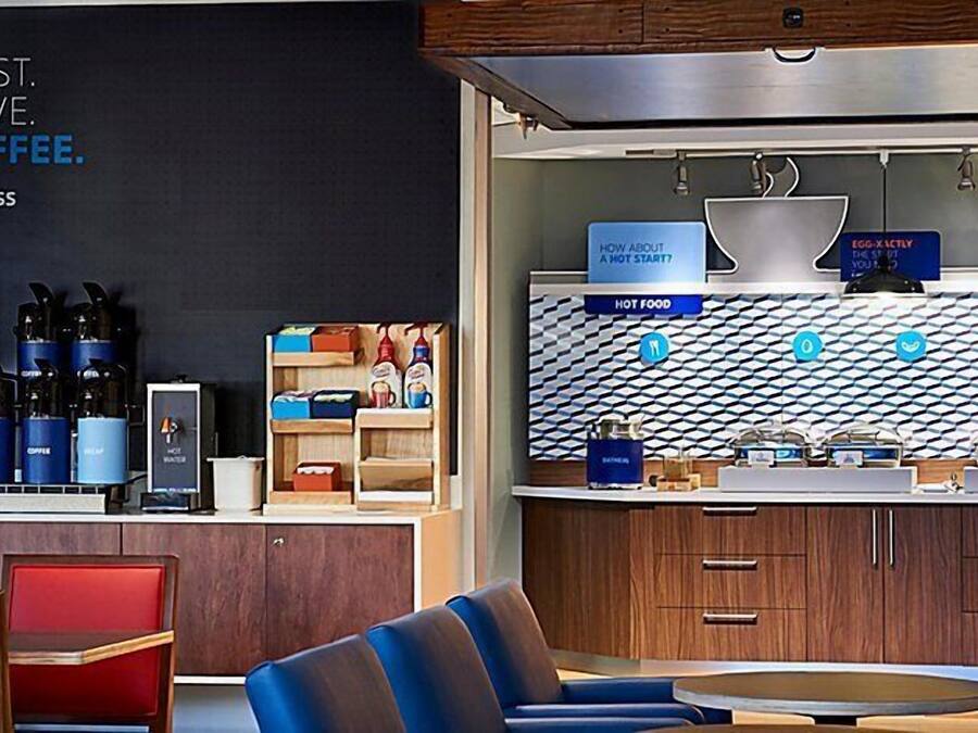 Een moderne koffiebar met een prikbord, een koffieapparaat en verschillende koffiecontainers.