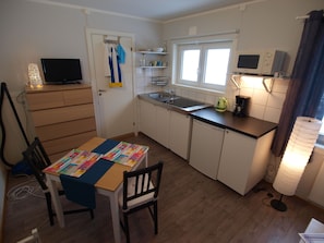 Uma cozinha compacta com uma mesa de jantar, cadeiras, micro-ondas e pia.