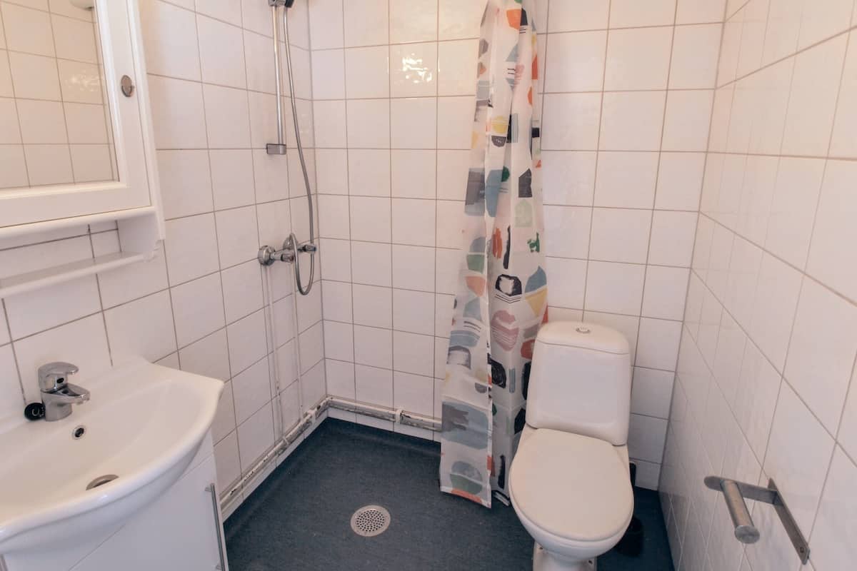 Une petite salle de bain propre, équipée de toilettes, d’un lavabo et d’une douche.