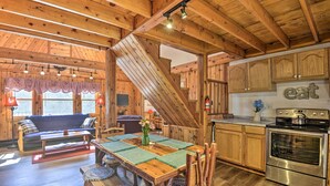 A wooden interior with a dining area, kitchen, and a staircase. - Springwater Cabin Near Hiking, Lakes, & Vineyards (Springwater)