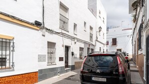 Una calle estrecha con edificios blancos, un coche Citroen estacionado y cajas eléctricas a la vista.