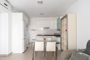 Una cocina moderna con armarios blancos, una mesa de comedor de vidrio y un horno empotrado.