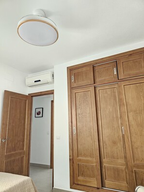 A room with a bed, wooden wardrobe, and an air conditioning unit. - Beautiful Apartment "Entre Vientos" in the City Center with Air Conditioning (Conil de la Frontera)