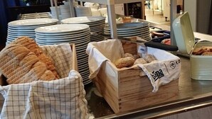 A buffet setup with bread, pastries, and stacked plates. - Torpomoen (Al)