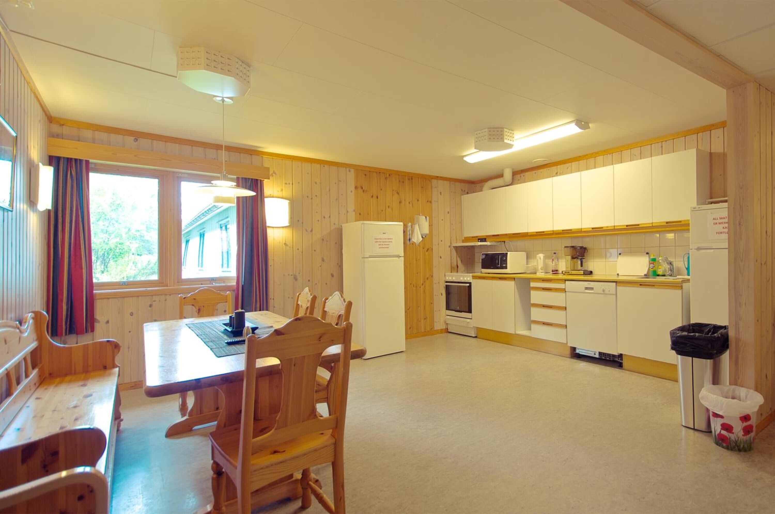 A compact kitchen with wooden cabinets, a refrigerator, a microwave, and a sink.