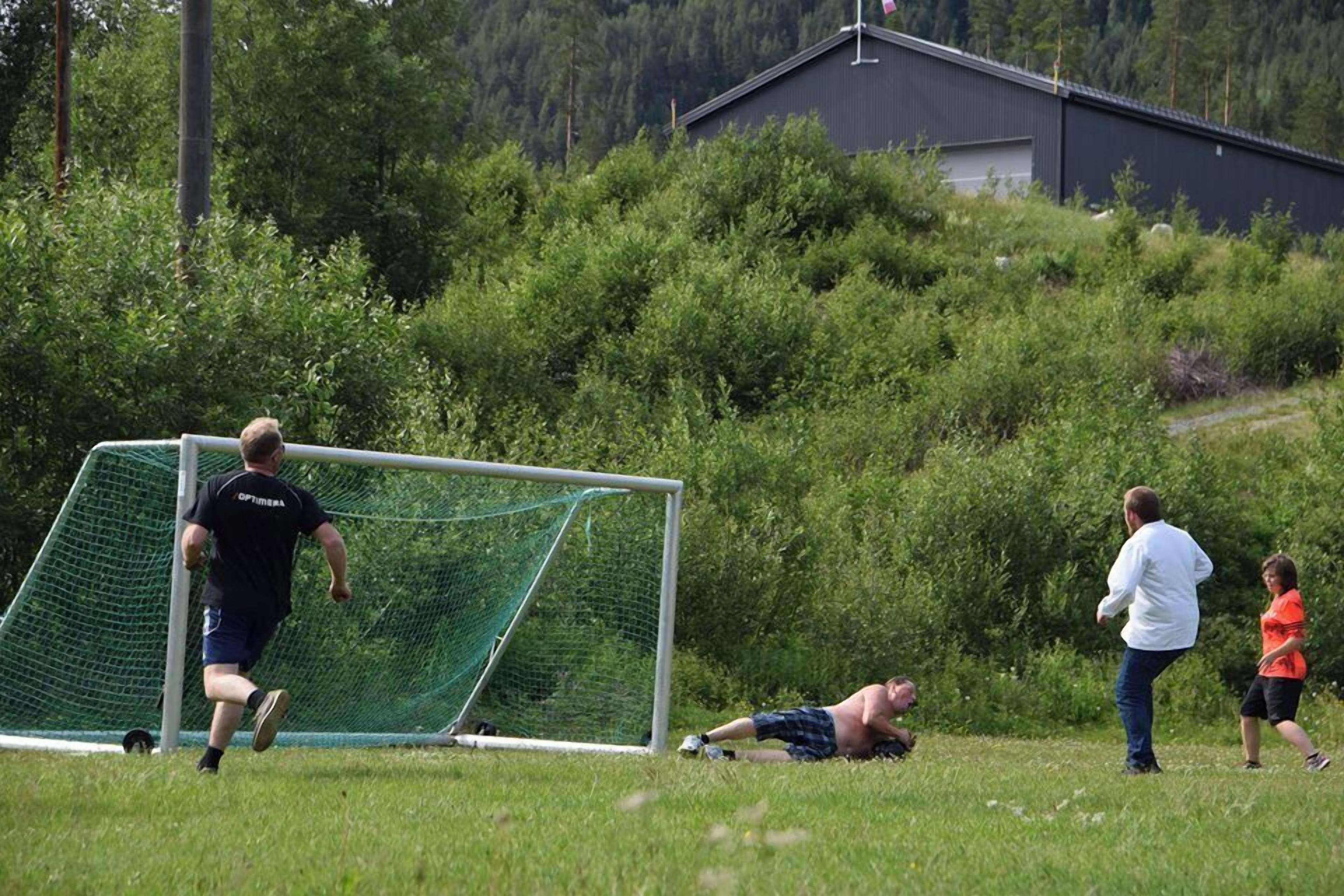 A soccer field with a goalpost, a person running, and another lying on the ground.