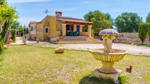 Una casa de piedra con un patio, una fuente y una pequeña estatua.