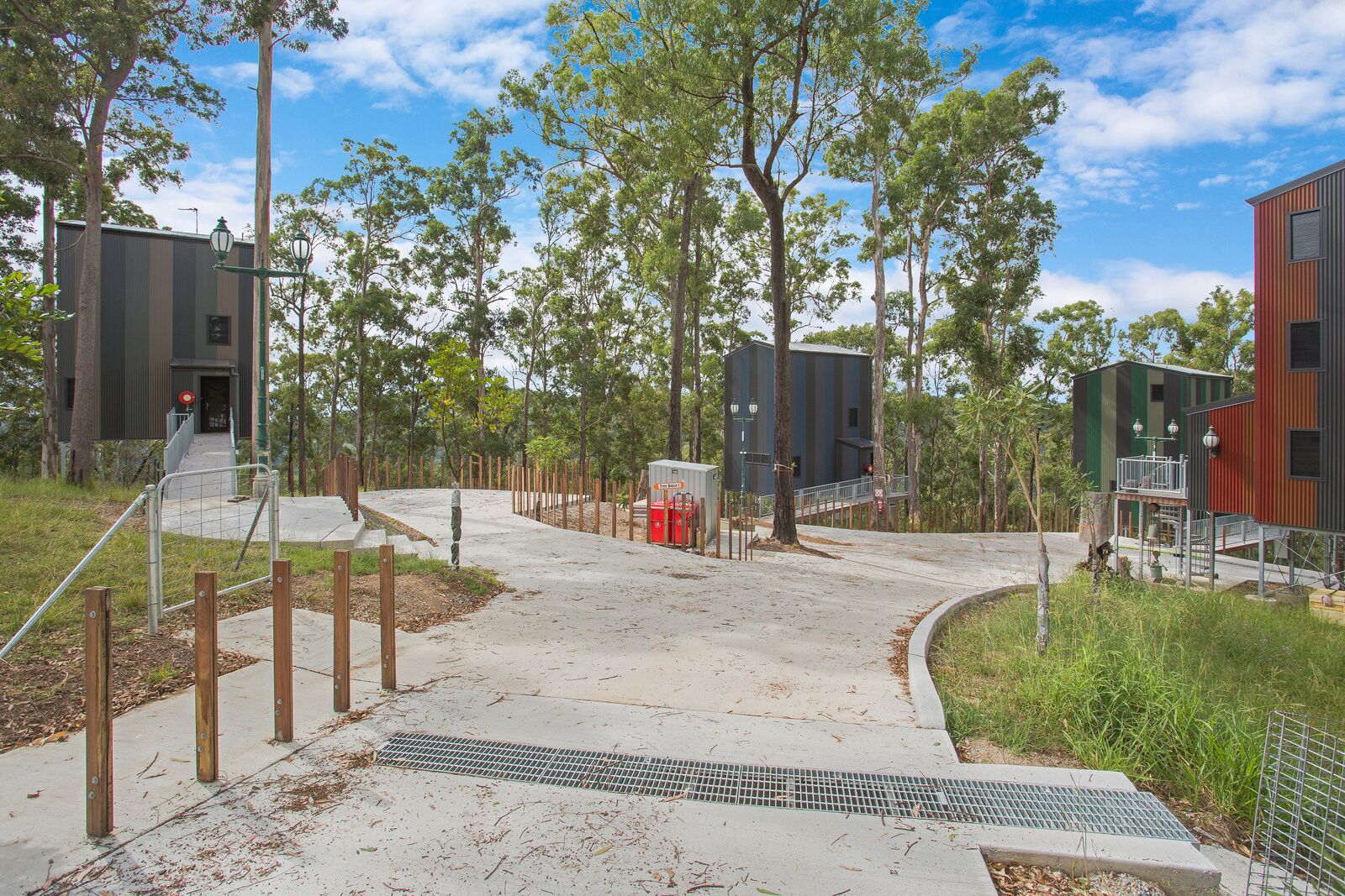 A modern building with a metal exterior, surrounded by trees and a clear sky.