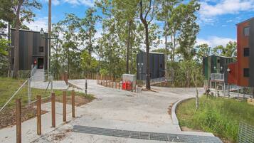 A modern building with a metal exterior, surrounded by trees and a clear sky.
