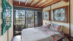 A bedroom with a large bed, a view through a sliding glass door, and decorative metalwork on the walls. - Treehouse #3, Tri-Level, Large BBQ. Amazing views (Austinville)