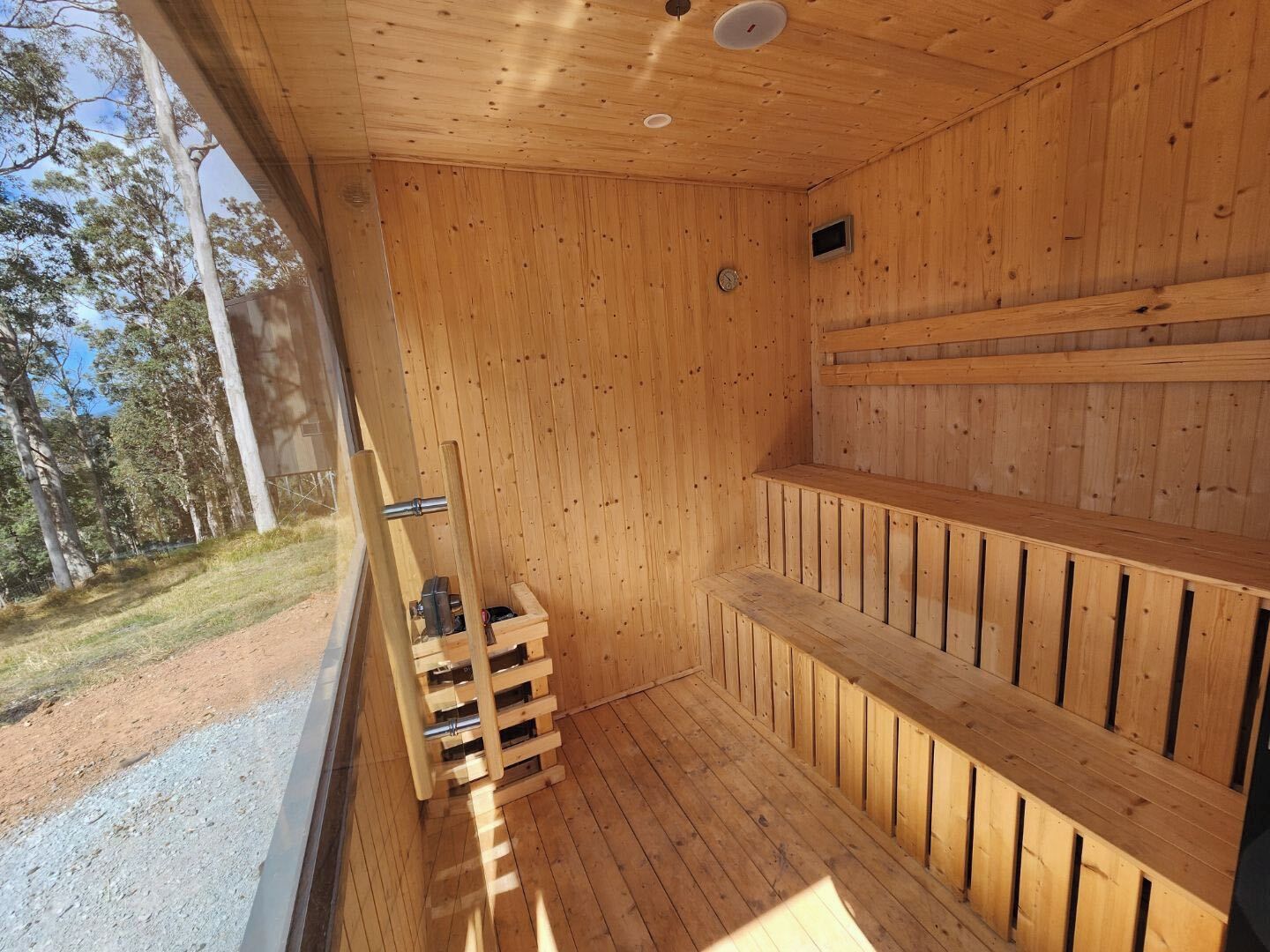 Un sauna avec des murs et des bancs en bois, une fenêtre et une porte.