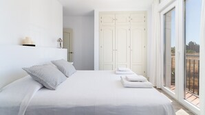 Une chambre avec un grand lit, une armoire et un balcon avec vue.