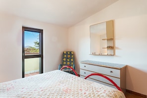 A bedroom with a bed, a dresser, a mirror, and a window with a view.